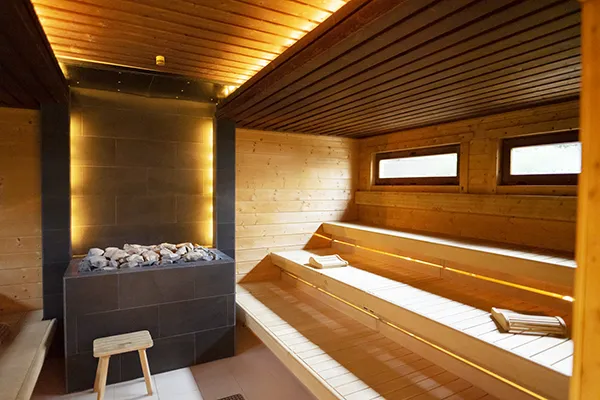 Innenraum einer Sauna mit moderner Ofenanlage und Holzliegen bei SAUNA PUR
