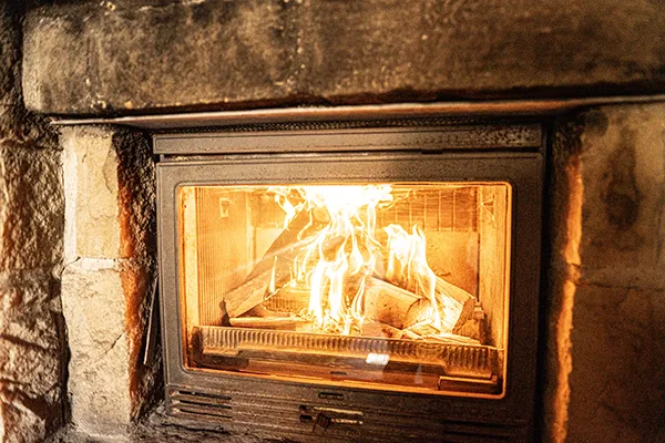 Kaminofen mit loderndem Feuer in der traditionellen Sauna bei SAUNA PUR